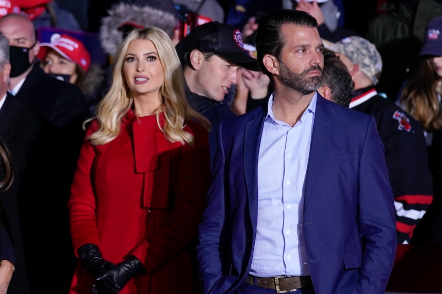 Ivanka Trump and Donald Trump Jr stand listening to a speech