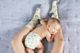 A mum's legs wearing avocado socks with a baby wearing an avocado printed nappy.