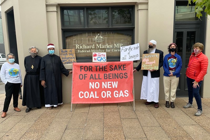 Líderes cristianos, musulmanes y budistas de pie frente a la oficina del diputado Richard Marles sosteniendo una pancarta de No nuevo carbón o gas.