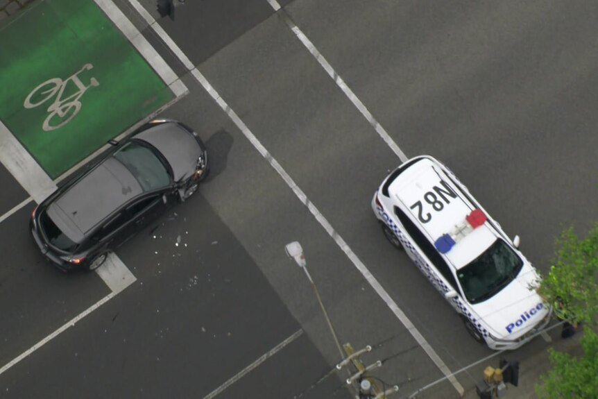 An aerial photo of a police car and damaged black sedan on a residential road.