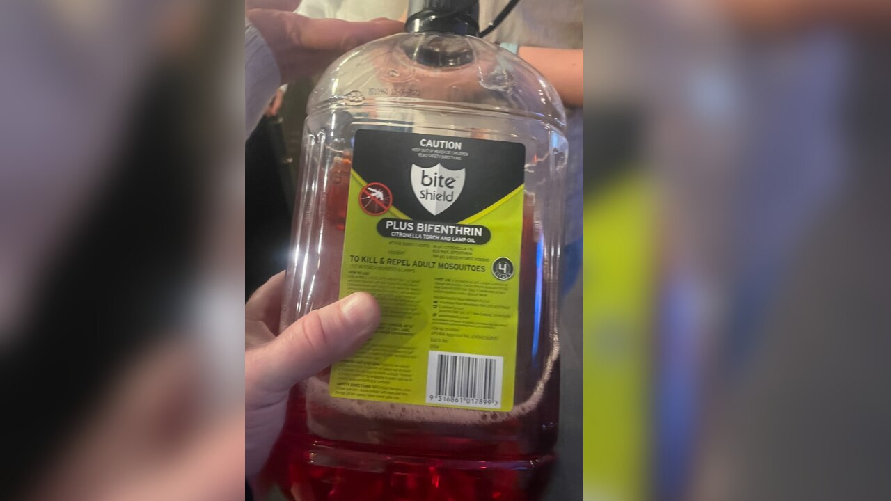 A plastic bottle full of red insect repellent liquid.