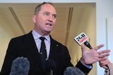 Barnaby Joyce raised a hand as he speaks to press outside Parliament House.