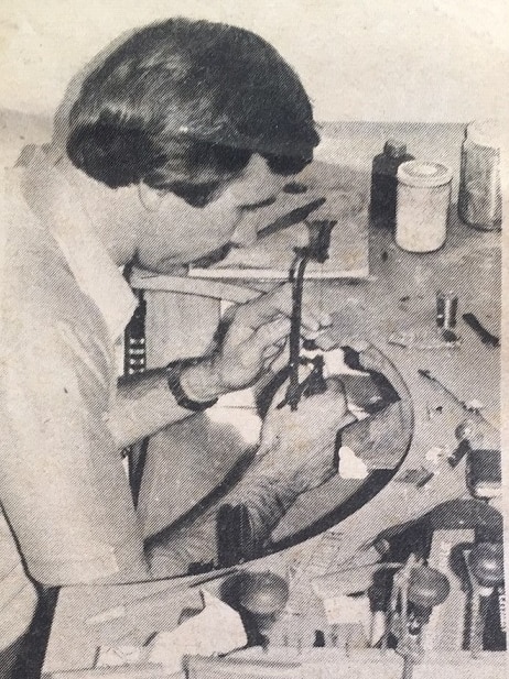 A black-and-white newspaper photo of a man repairing something in a jewellery store