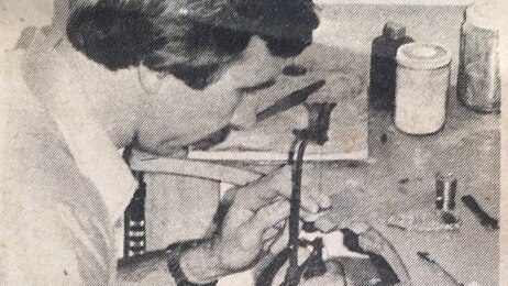 A black-and-white newspaper photo of a man repairing something in a jewellery store