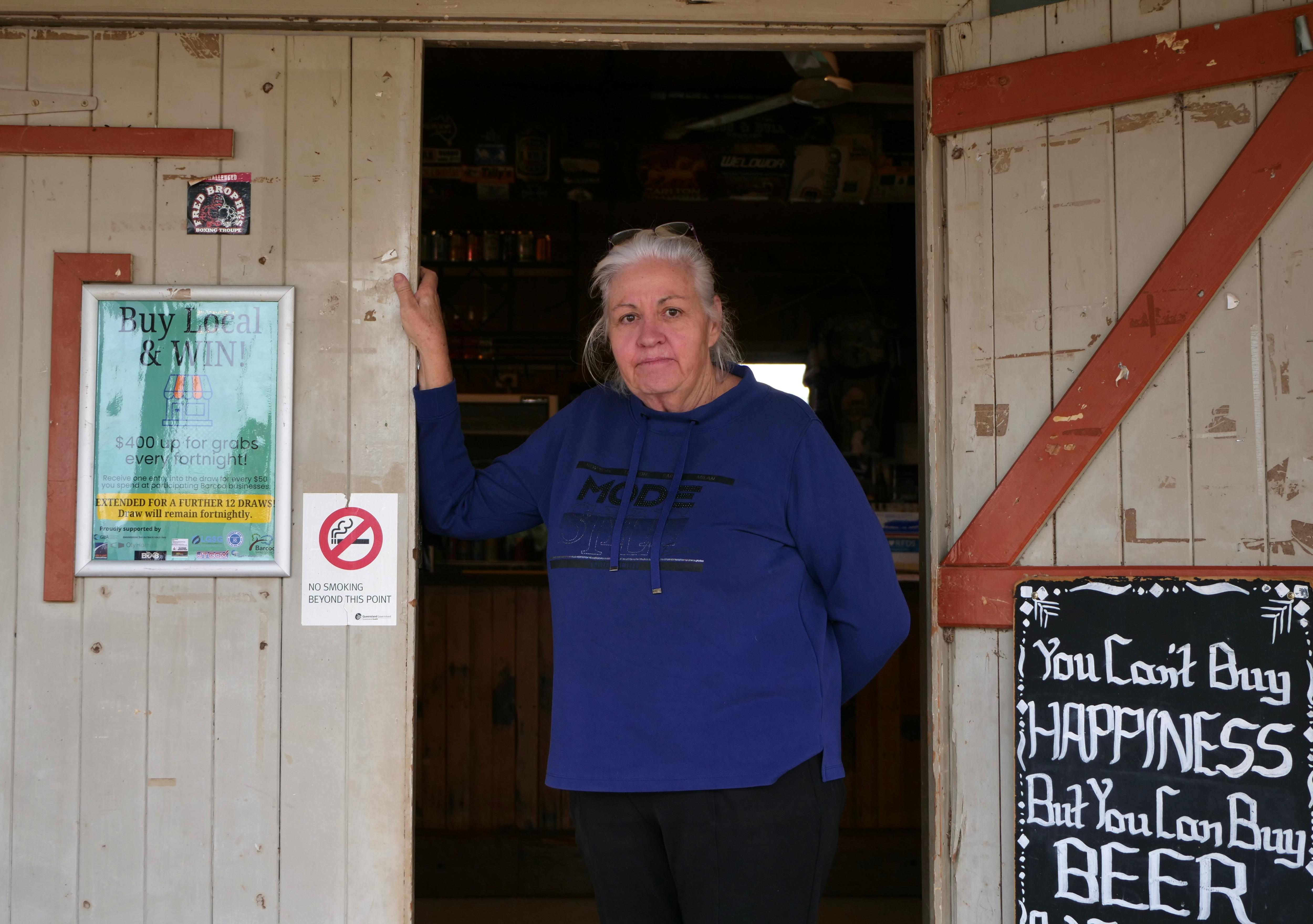 Woman in a blue jumper stands in a doorway at a pub. 