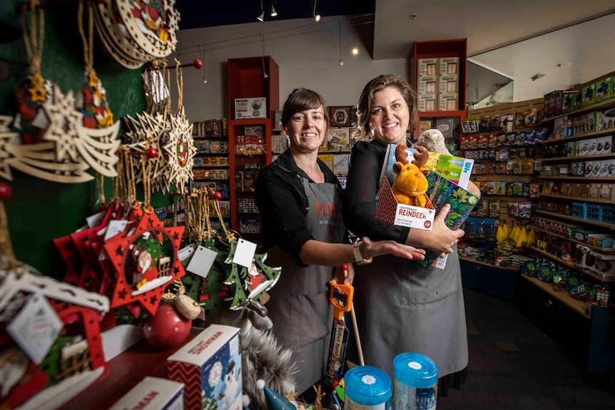 Two women hold toys in a shop