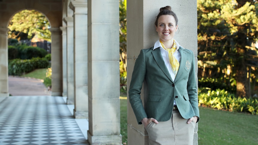 Swimmer Ellie Cole stands leaning against a pillar, smiling at the camera.