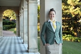 Swimmer Ellie Cole stands leaning against a pillar, smiling at the camera.