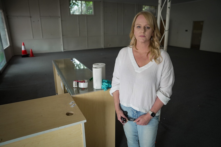 A woman wearing a white top and jeans standing in an empty shop