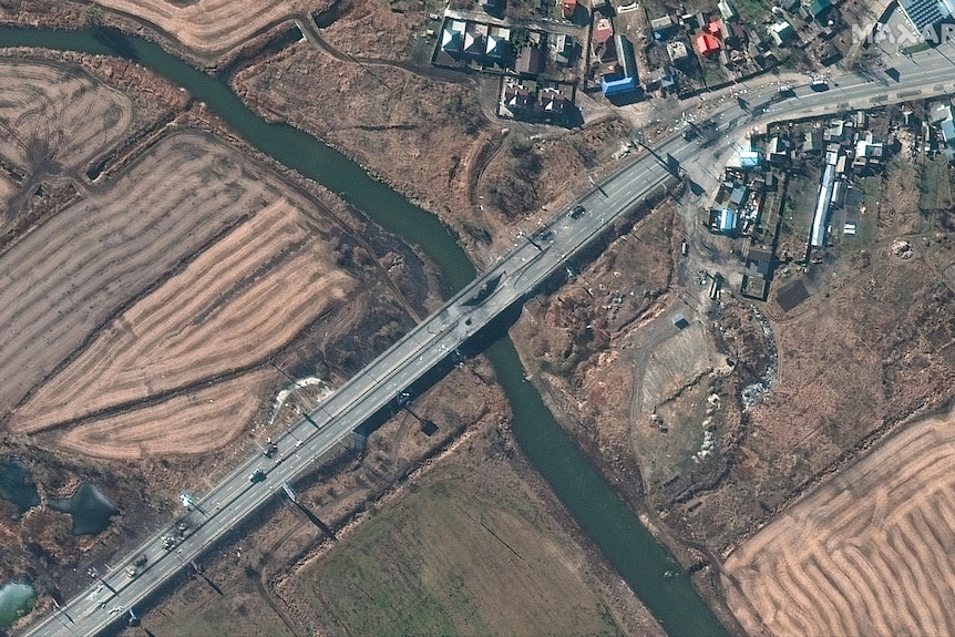 Destroyed vehicles on a damaged bridge seen from above.