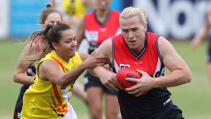 An opponent tries to tackle Hannah Mouncey as she plays football for the Darebin Falcons in the VFLW.