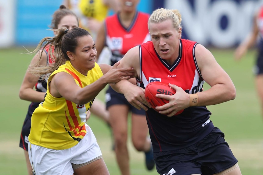 An opponent tries to tackle Hannah Mouncey as she plays football for the Darebin Falcons in the VFLW.