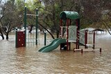 A playground is half submerged in rising floodwaters.