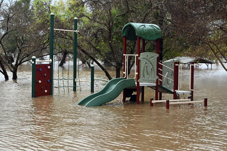 A playground is half-submerged in rising floodwaters.