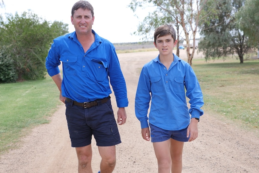 Jason and Charlie Rogers walk down the driveway towards the camera, wearing blue shirts.