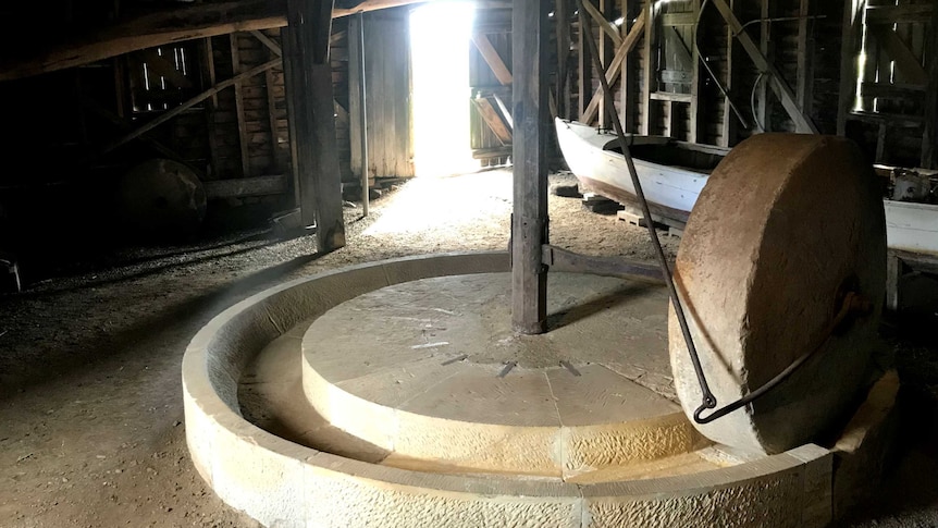 An old stone apple crusher in a wooden building