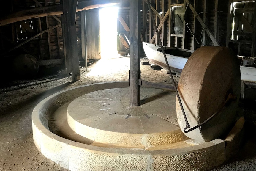An old stone apple crusher in a wooden building