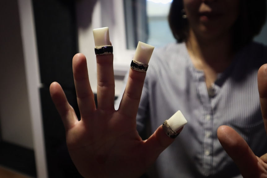 Photo of a hand wearing tsume, the tool used to pluck the Koto instrument.