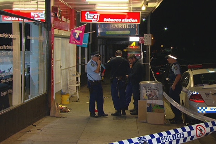 Police officers stand outside a tobacconist store