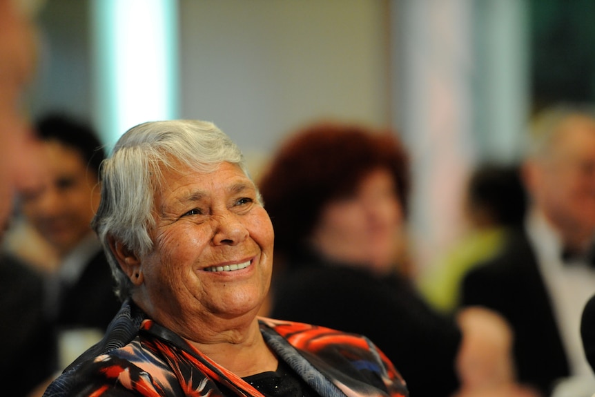 A woman with short white hair sitting and smiling