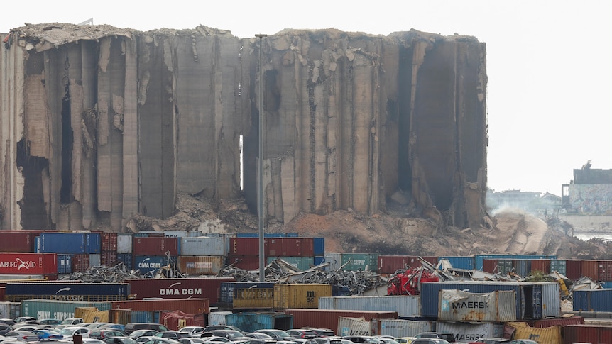 Dust rises as part of a damaged grain silo begins to collapse.