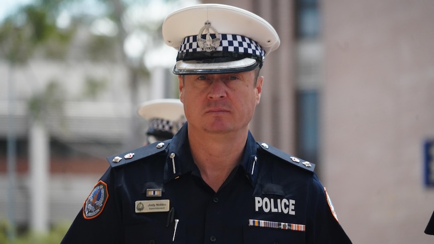 A man wearing a police hat and uniform looking directly at the camera with a neutral expression