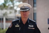 A man wearing a police hat and uniform looking directly at the camera with a neutral expression
