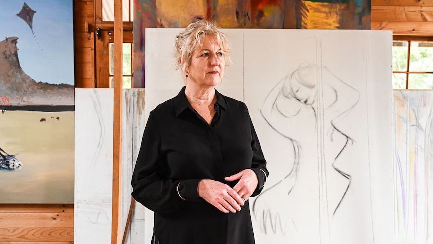 A woman in front of artwork looking pensive
