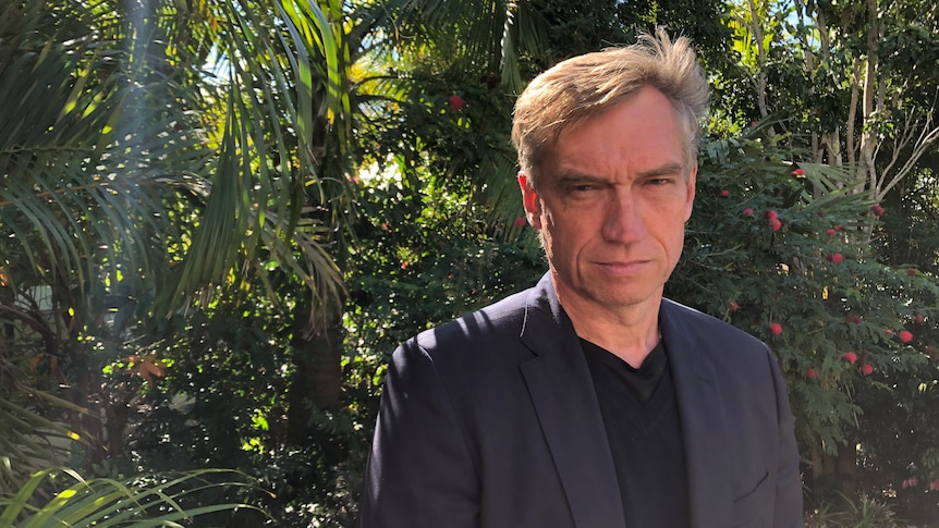 Stewart Dowrick stands in front of a garden.