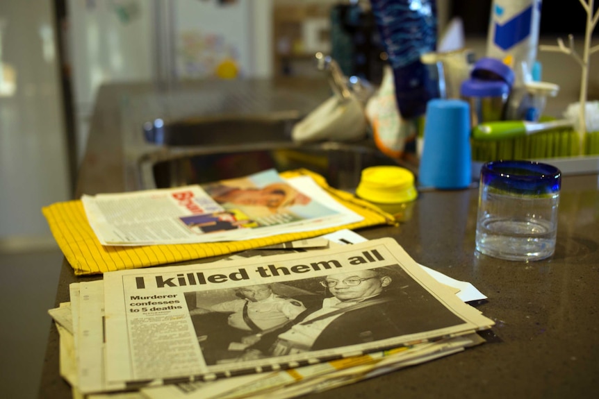 Newspaper clippings on a kitchen bench outline the murders committed by Lindsey Rose