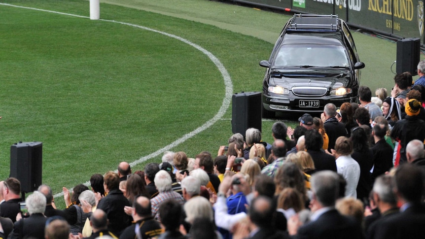 Richmond fans applaud as a hearse carrying Tom Hafey's coffin makes its way around the MCG in Melbourne.