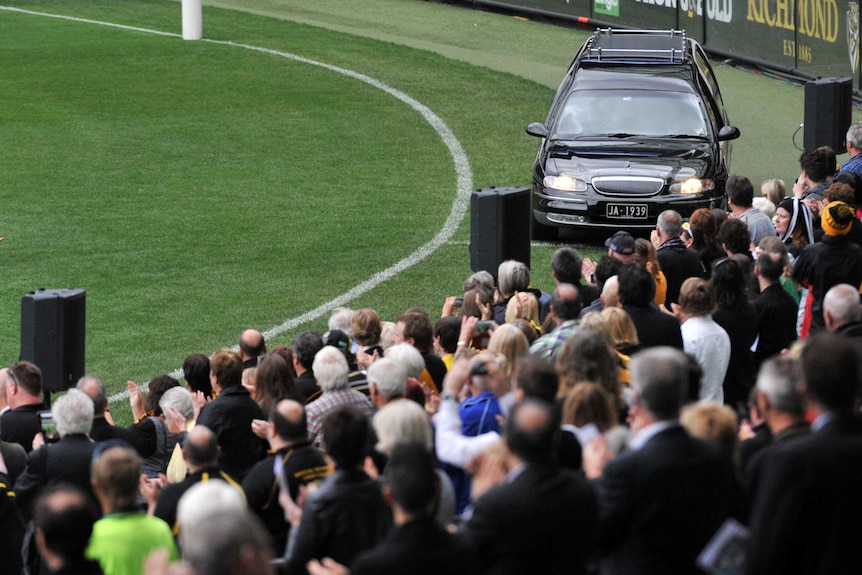 Richmond fans applaud as a hearse carrying Tom Hafey's coffin makes its way around the MCG in Melbourne.