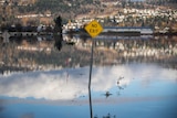 A "No Exit" sign is seen along the side of a flooded dead-end road