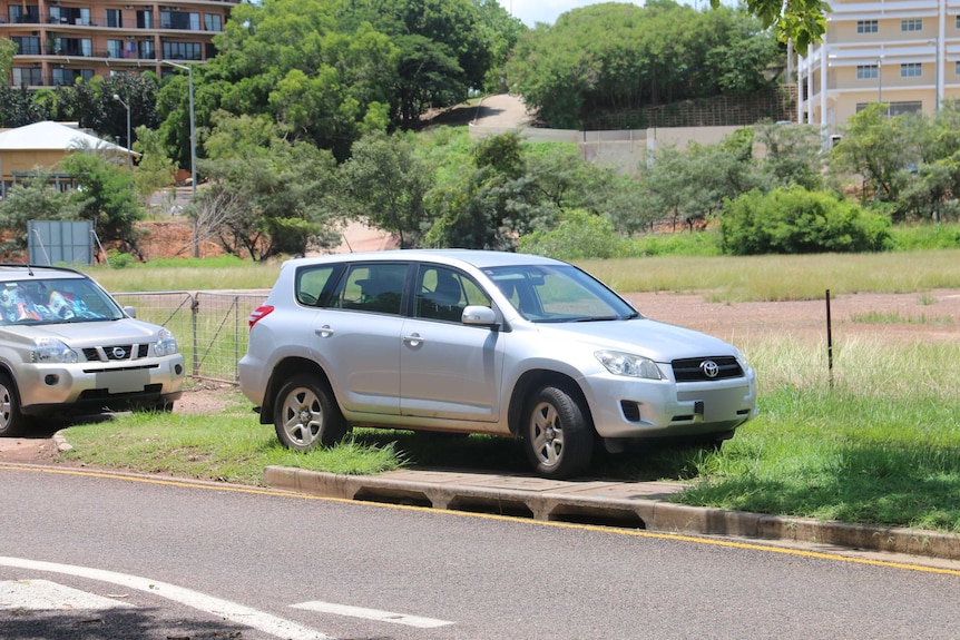 Two cars parked on grass verges along the side of the road.