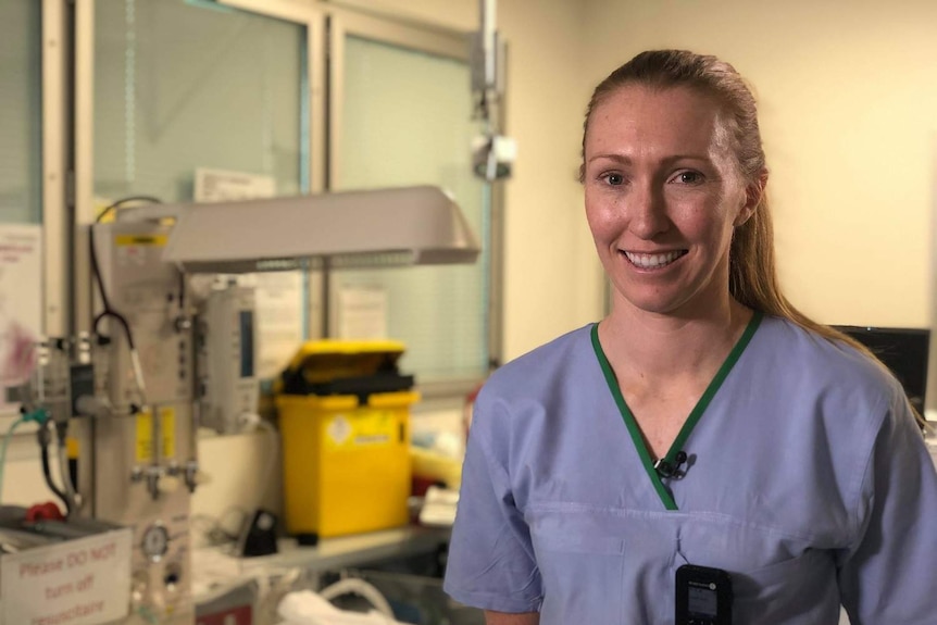 Doctor Tiarna Ernst poses in her blue scrubs at hospital.