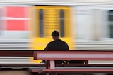 A man on a bench as the train whizzes past.