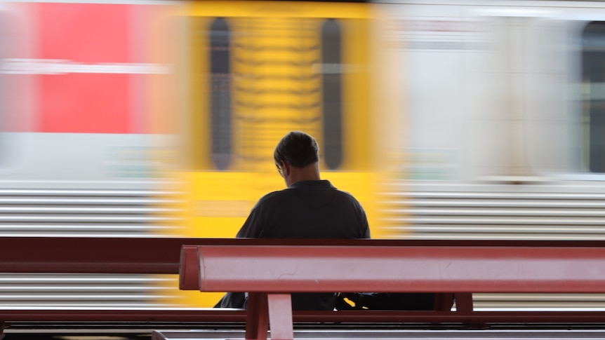 A man on a bench as the train whizzes past.