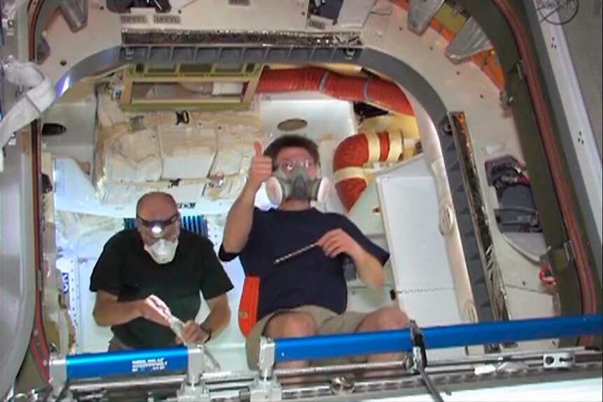 ISS commander Oleg Kononenko (R) and flight engineer Don Pettit signal the capsule's successful opening.