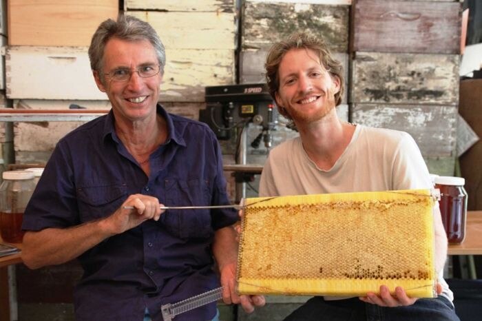 Stuart Anderson and his son Cedar hold a flow hive in their shed.
