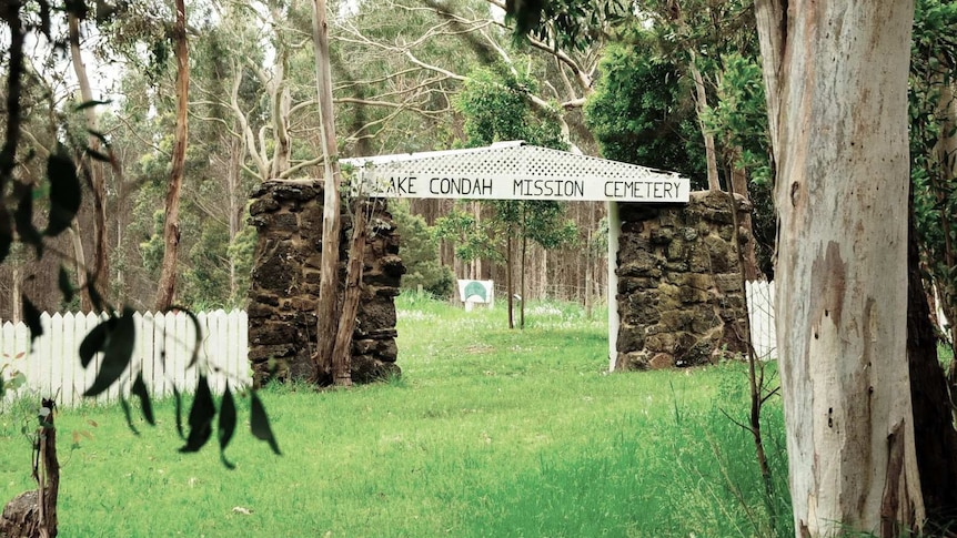 The entry to a verdant cemetery in bushland.