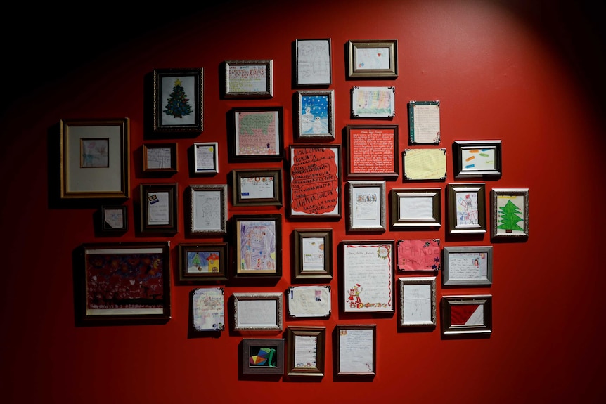 Framed letters to Santa hang on a red wall in Finland.