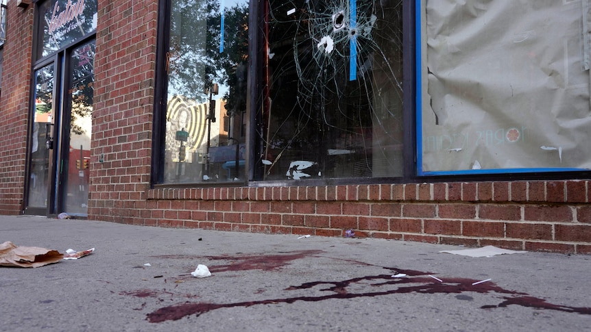 Blood is seen at the scene of a fatal overnight shooting as bullet holes are seen in the window above.