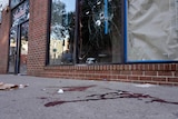 Blood is seen at the scene of a fatal overnight shooting as bullet holes are seen in the window above.