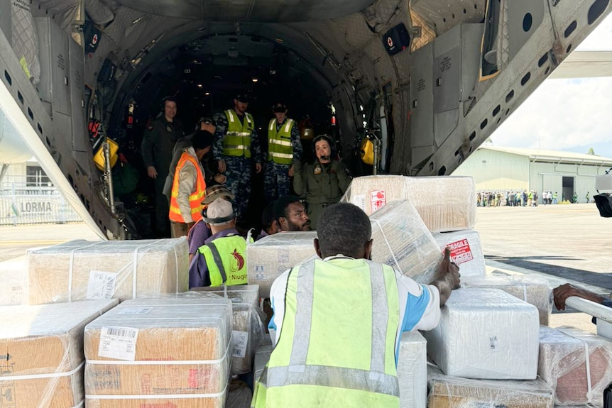 Boxes of aid being loaded onto a helicopter by staff.