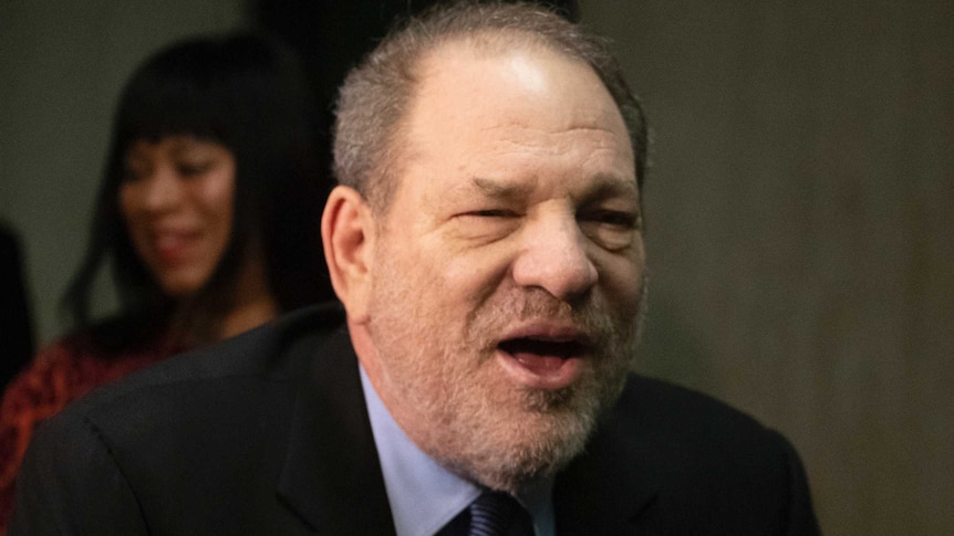 Harvey Weinstein walks into court. He is stooped over with one eye open, partially smiling