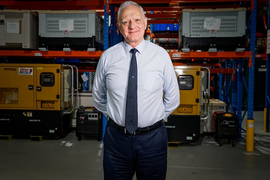 Professor Len Notaras stands inside a warehouse, smiling at the camera.