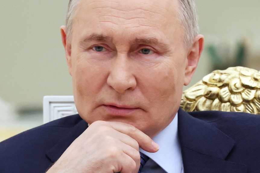Vladimir Putin resting his chin on his hand 
