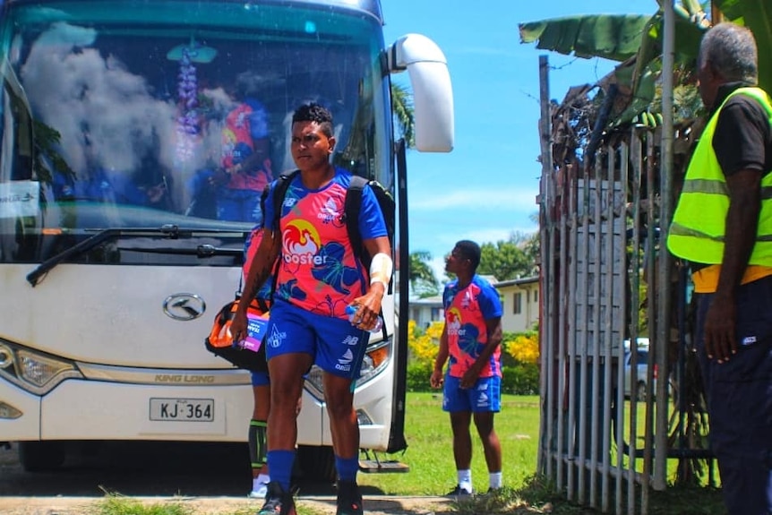 female athlete getting off a bus in training uniform 