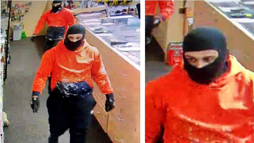 CCTV still of two men in orange hi-viz shirts wearing balaclavas in a gun shop.