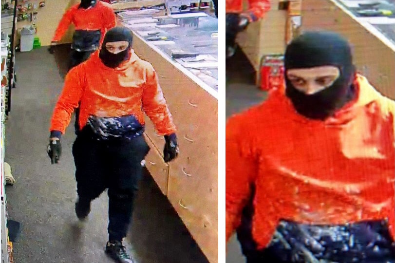 CCTV still of two men in orange hi-viz shirts wearing balaclavas in a gun shop.